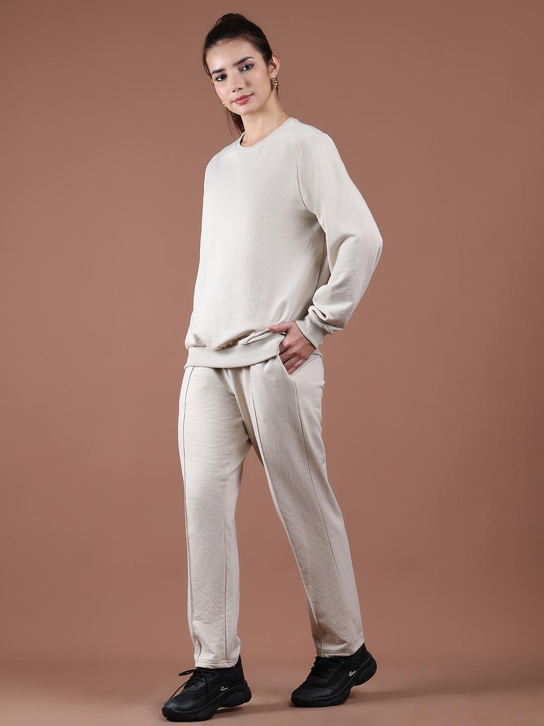 Woman wearing a beige Tracksuits or Co-ords set against a brown background