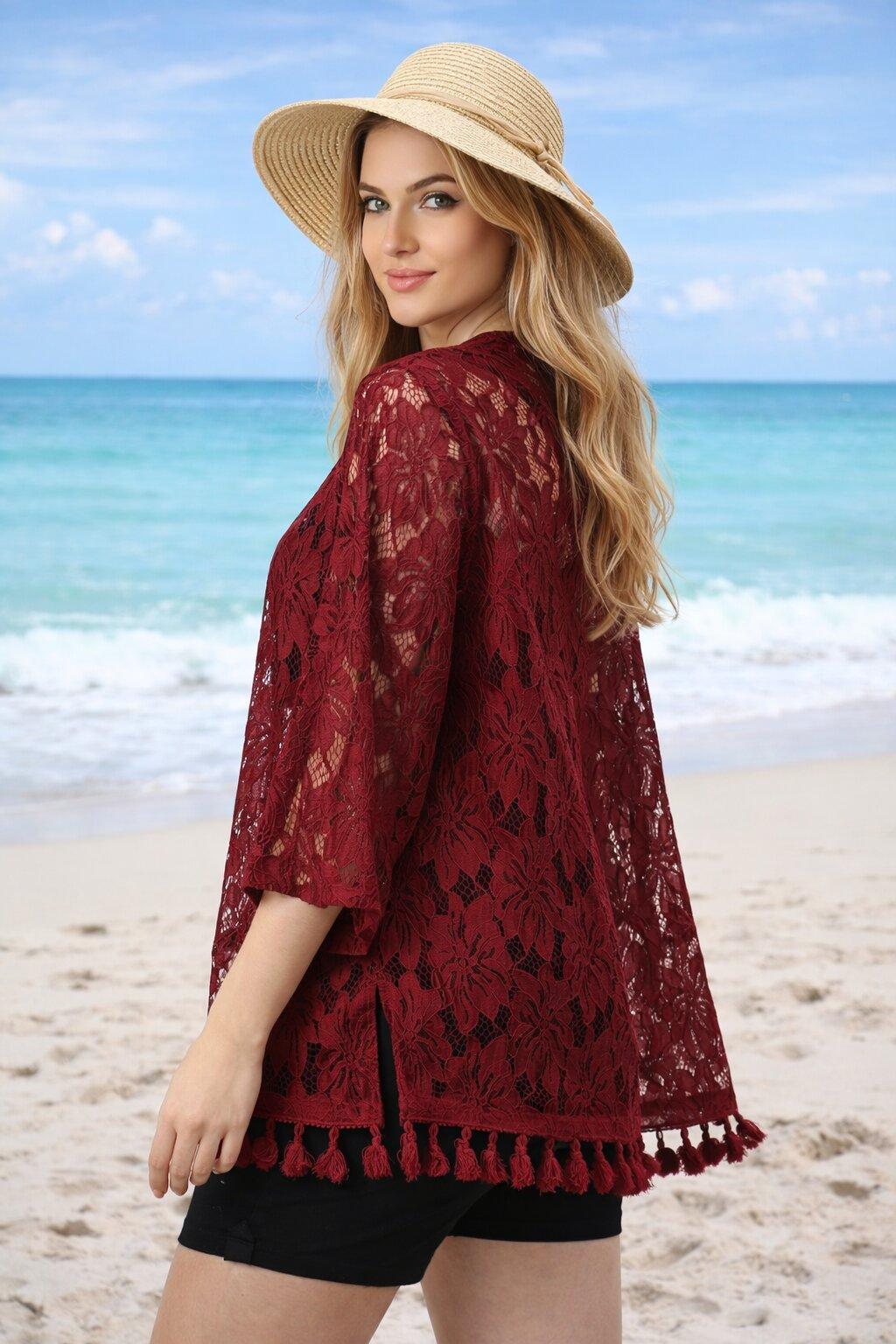 Woman wearing a red lace cover-up and straw hat on a beach