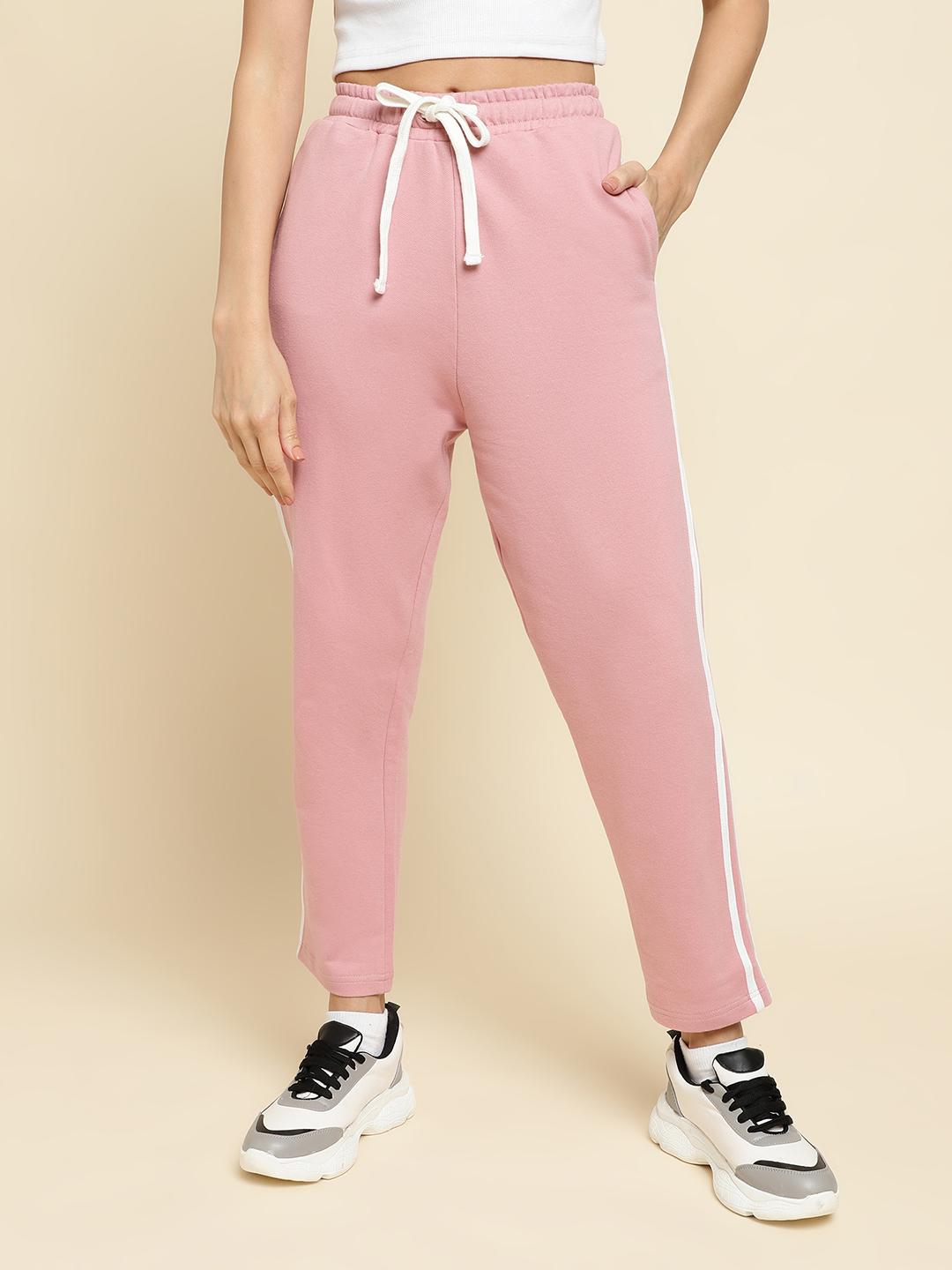 Person wearing pink jogger pants with a white stripe on a beige background