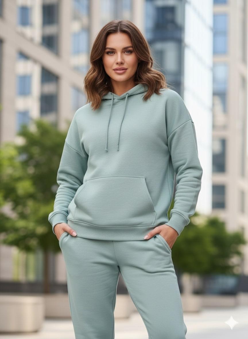 Woman wearing a sea green hoodie and pants in an urban setting
