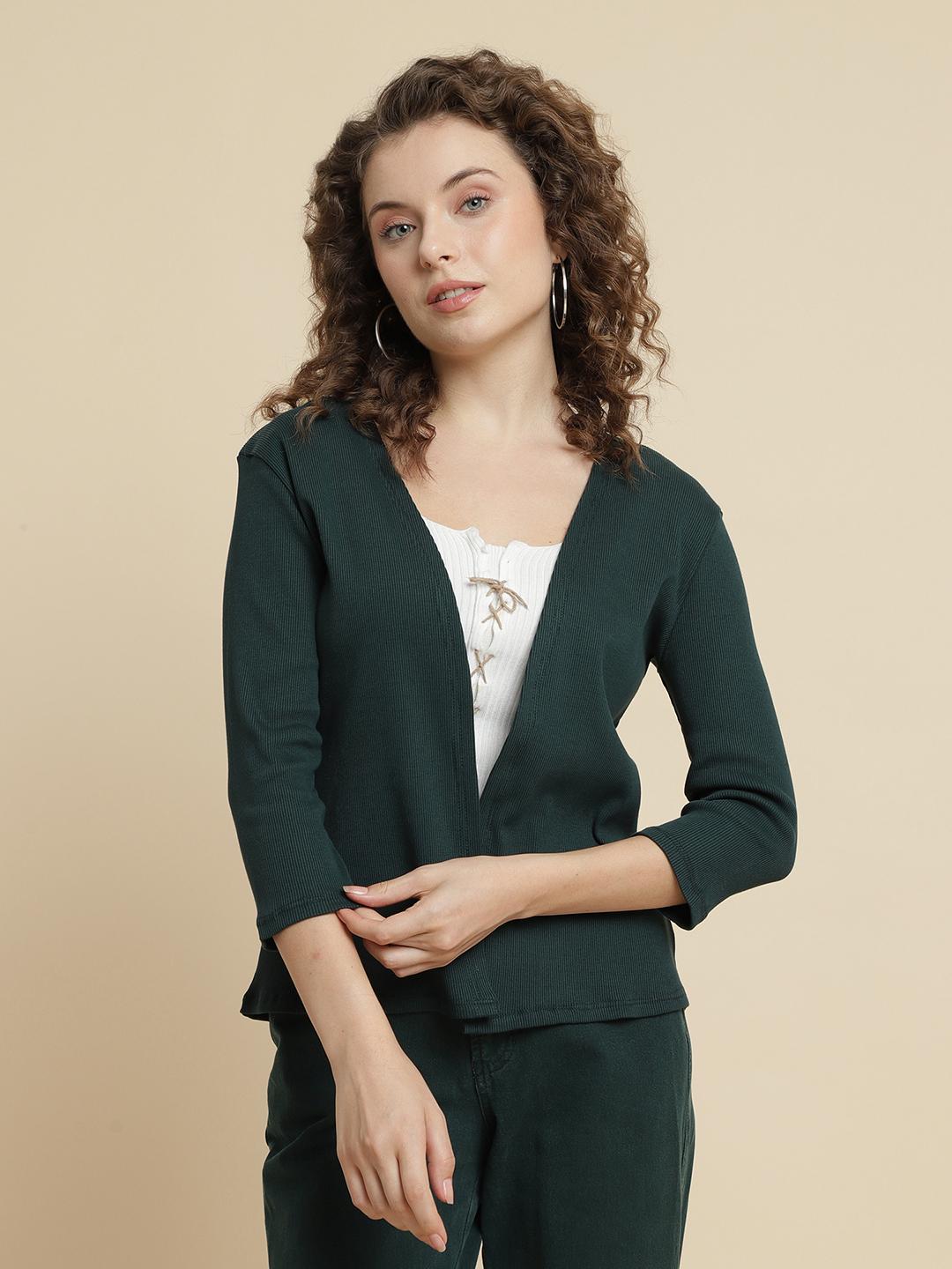 Woman wearing a green shrug against a beige background