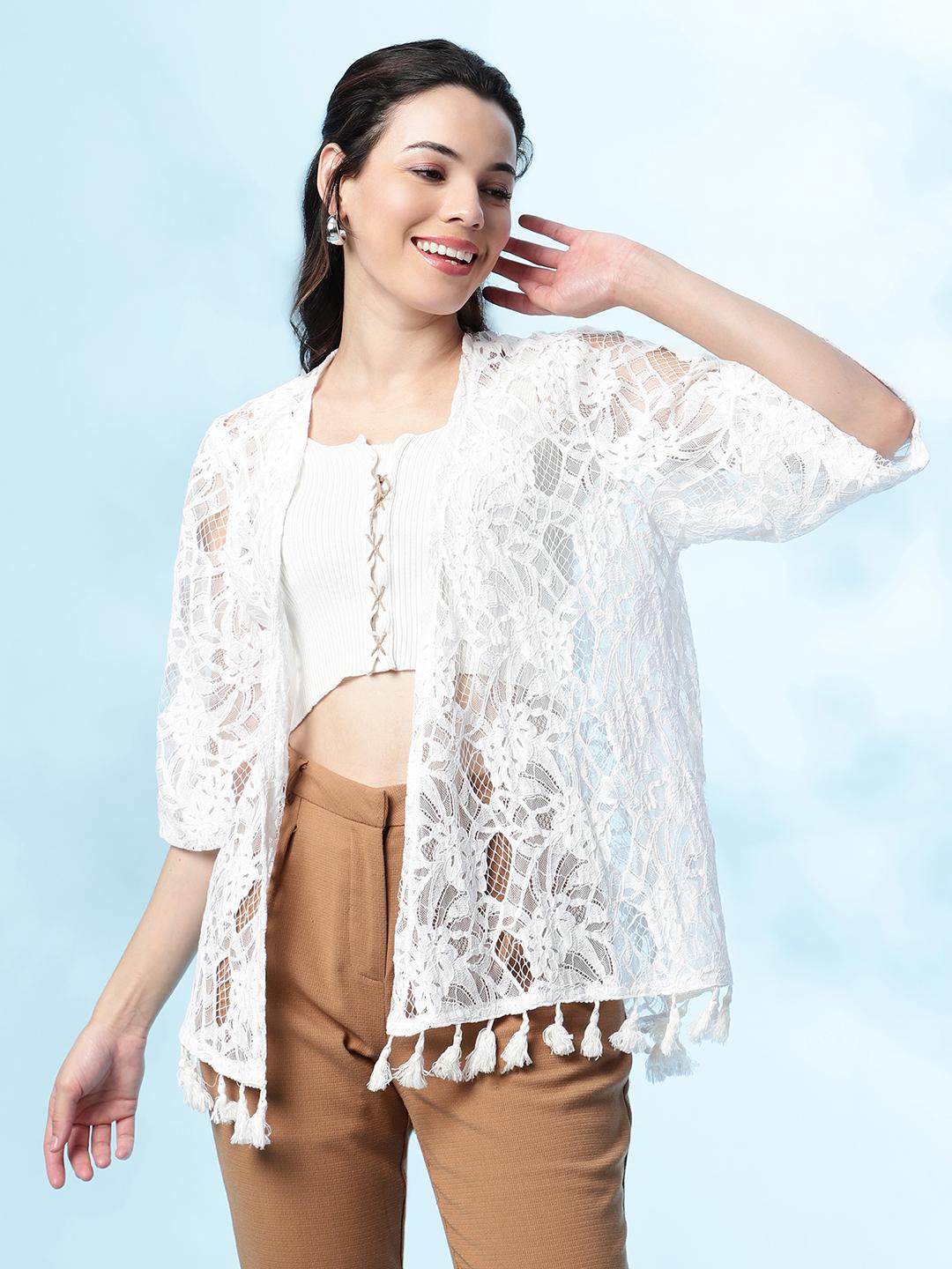 Woman wearing a white lace kimono-style top with tassels on a light blue background