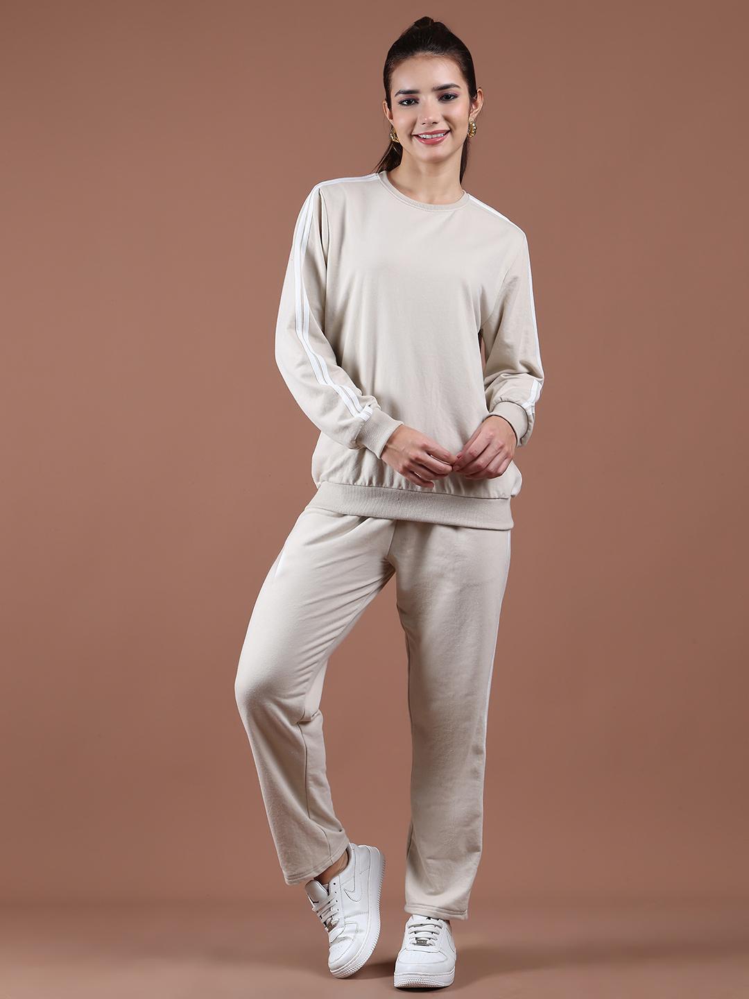 Woman wearing a beige tracksuit against a brown background