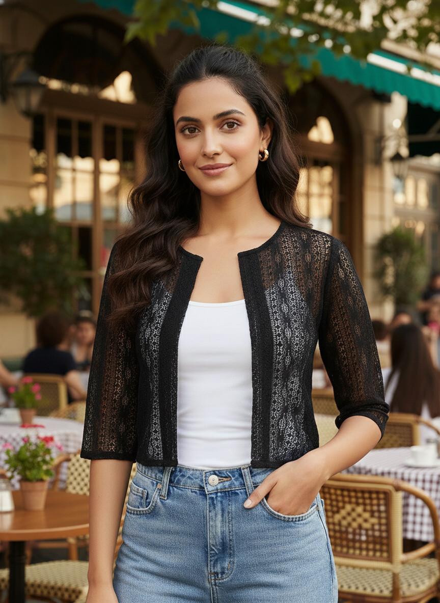 Woman wearing a black lace top over a white shirt and blue jeans in an outdoor setting.