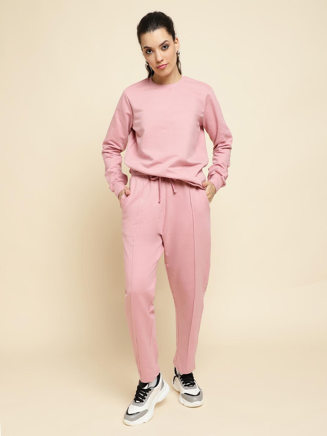 Person wearing a pink tracksuit on a beige background