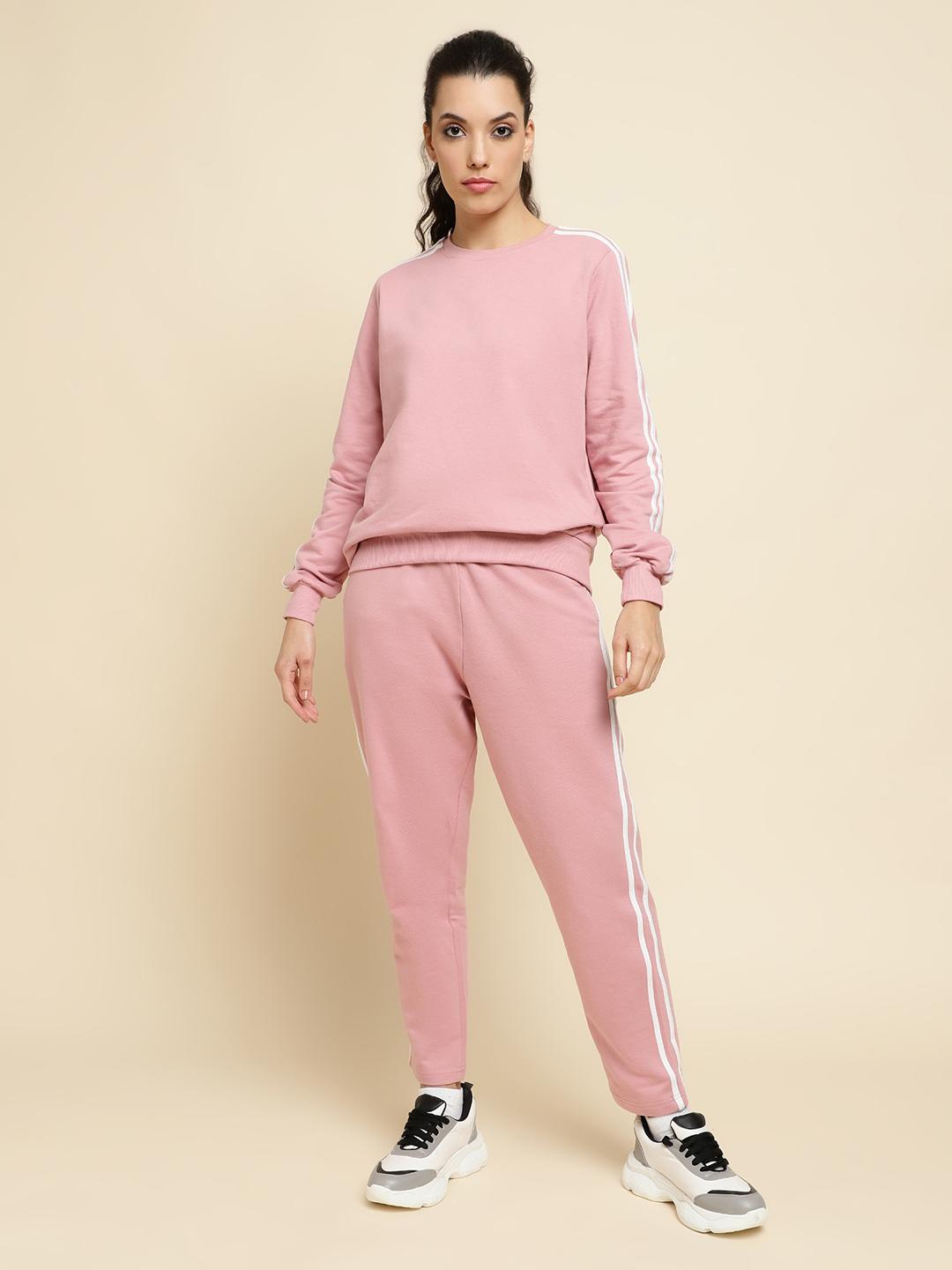 Woman wearing a pink tracksuit with a beige background