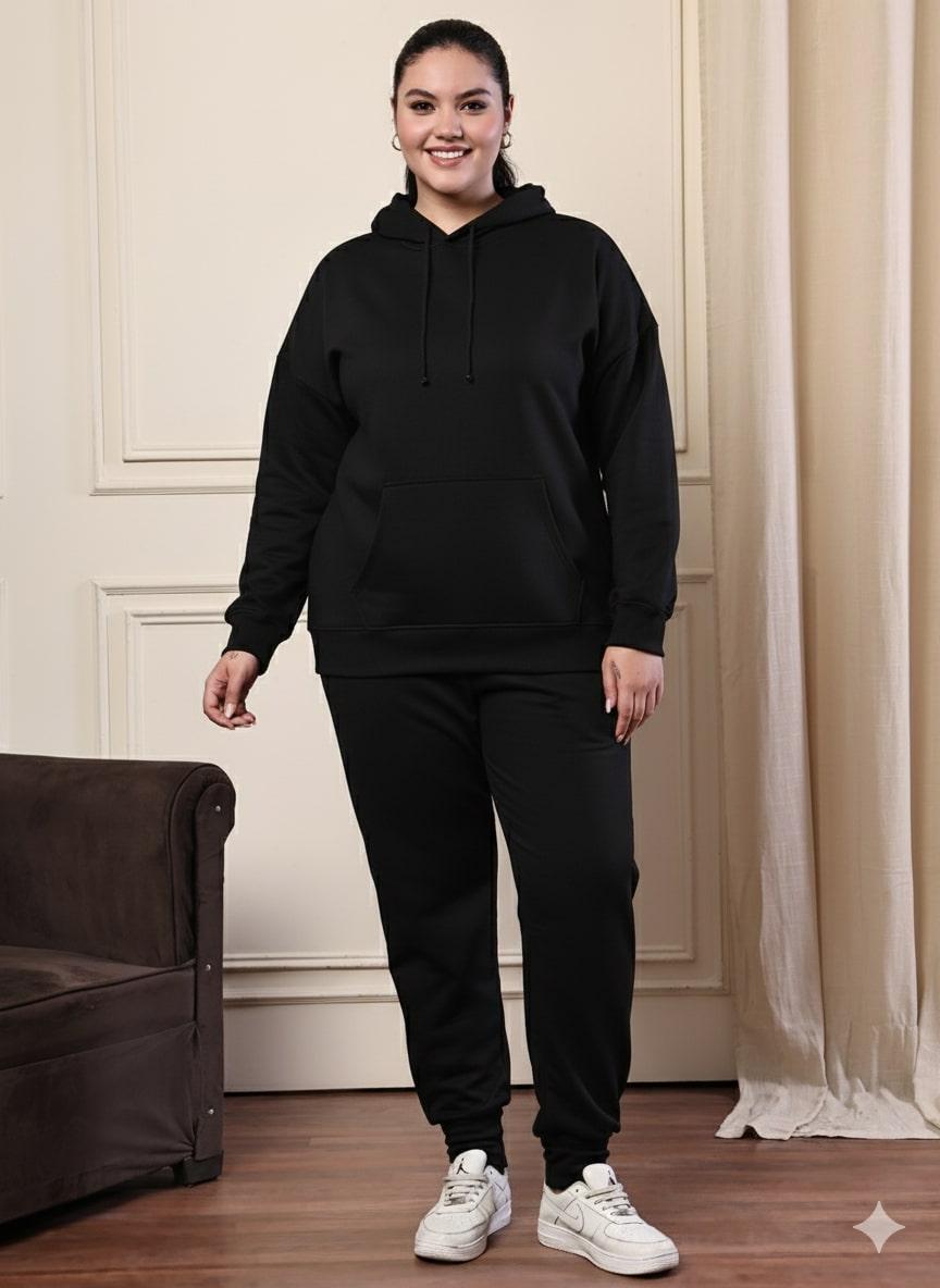 Woman wearing a black hoodie and black pants with white sneakers in a room.