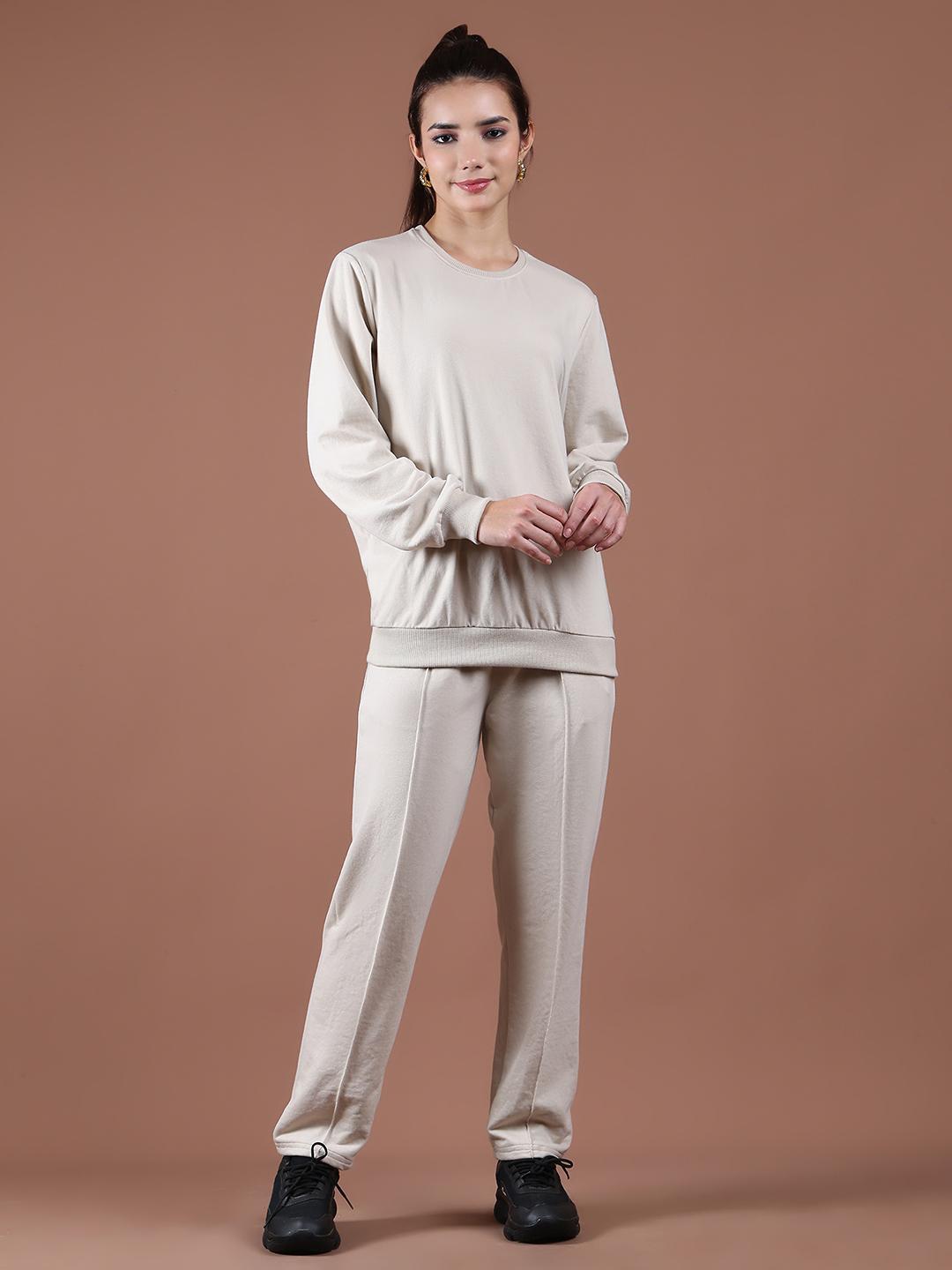 Woman wearing a beige tracksuit against a brown background