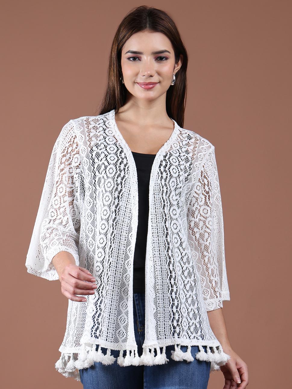 Woman wearing a white lace shrug over a black top on a brown background