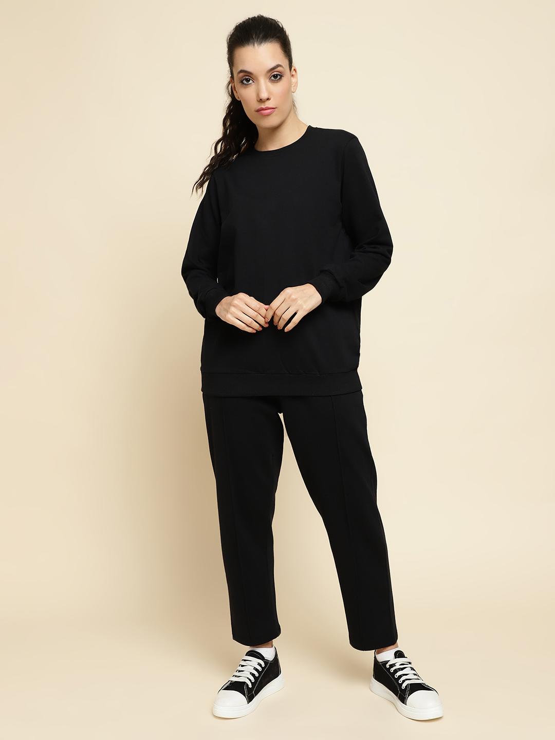 Woman wearing a black outfit with black and white sneakers on a beige background