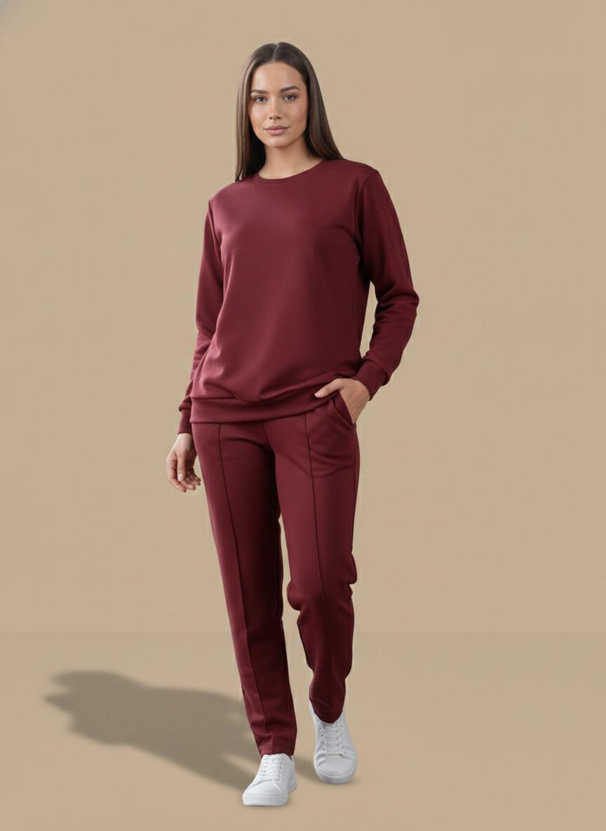 Woman wearing a maroon tracksuit on a beige background