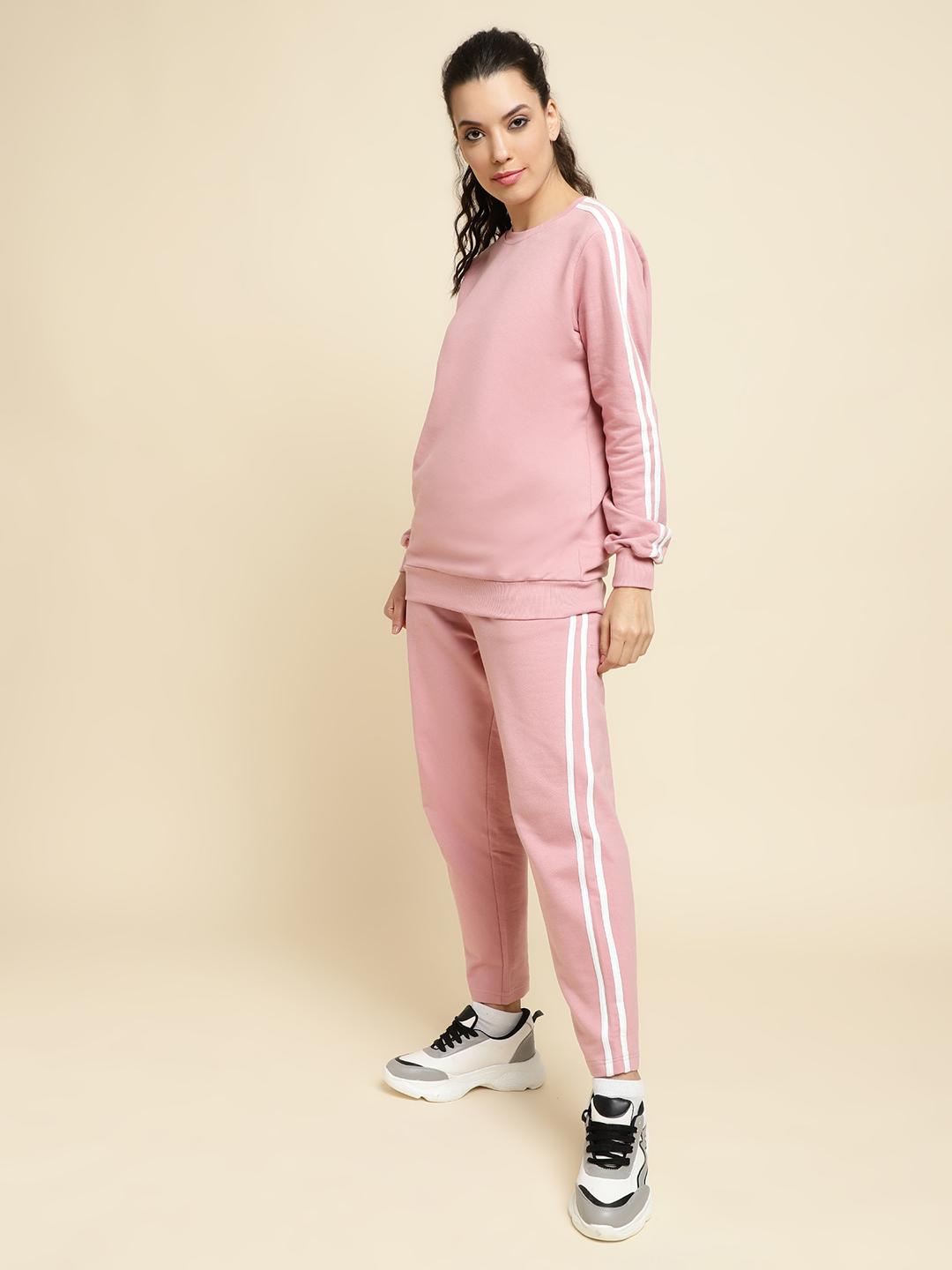 Woman wearing a peach tracksuit with white stripes on a beige background