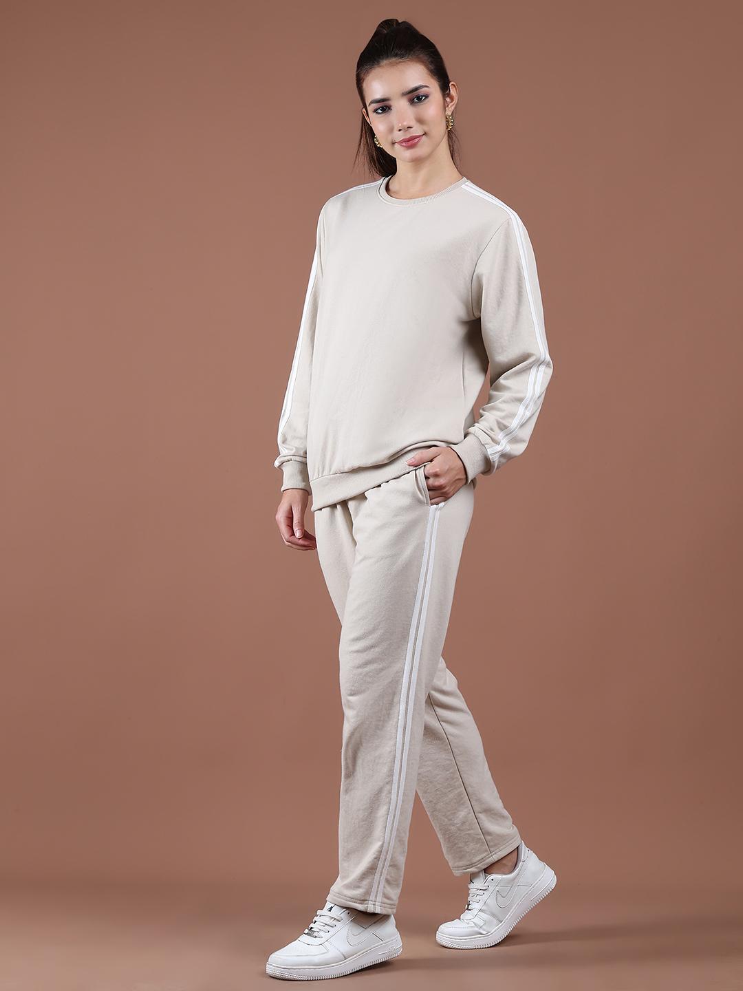 Woman wearing a beige co-ord set against a brown background
