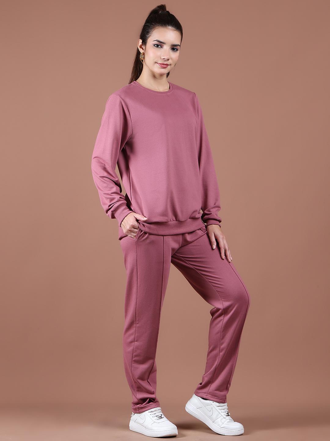 Woman wearing a mauve tracksuit against a brown background