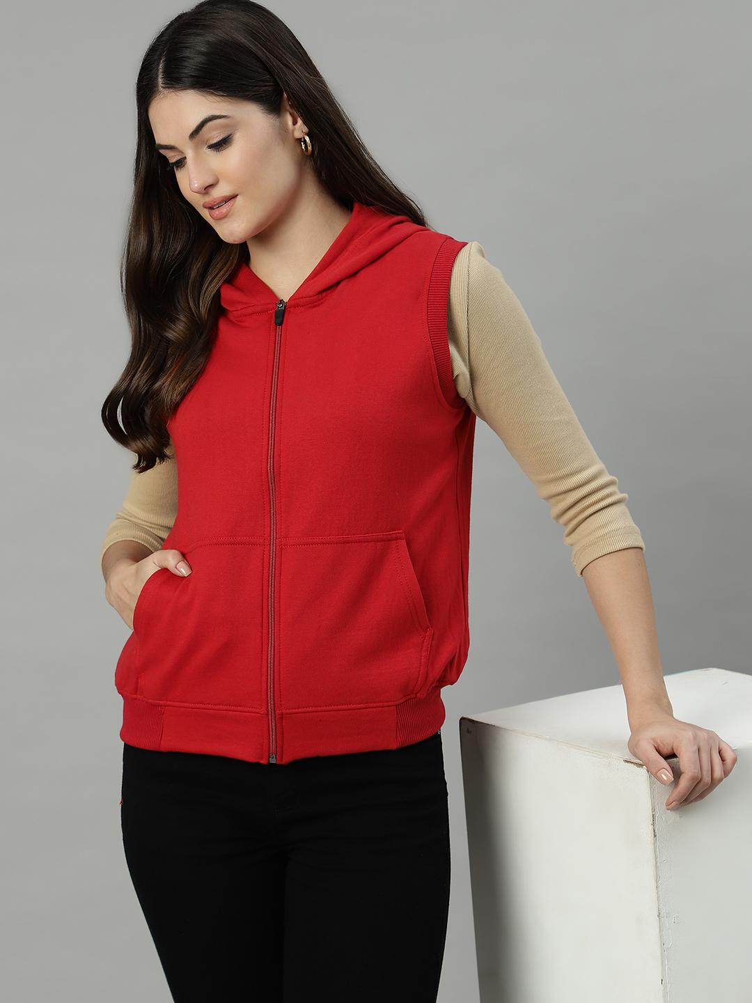 Woman wearing a red hoodie over a beige long-sleeve shirt on a gray background