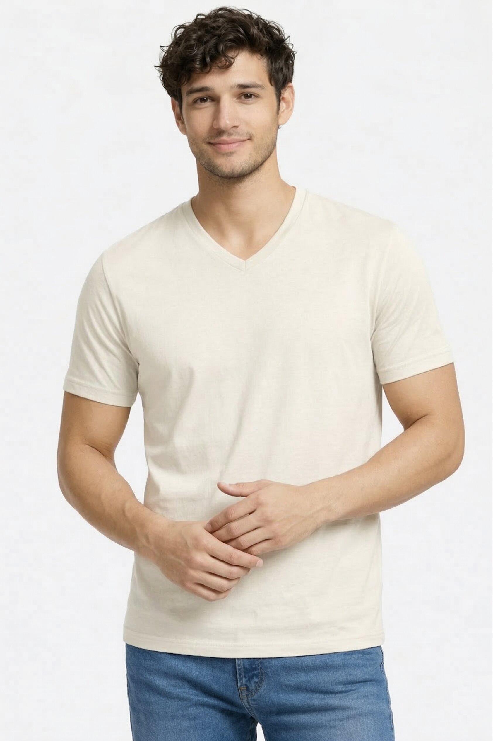 Man wearing a plain off white t-shirt and blue jeans on a light gray background