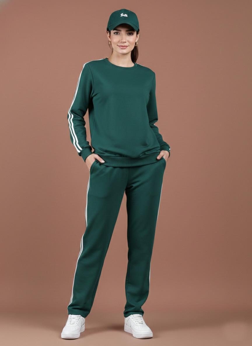 Woman wearing a green tracksuit with white stripes on a brown background