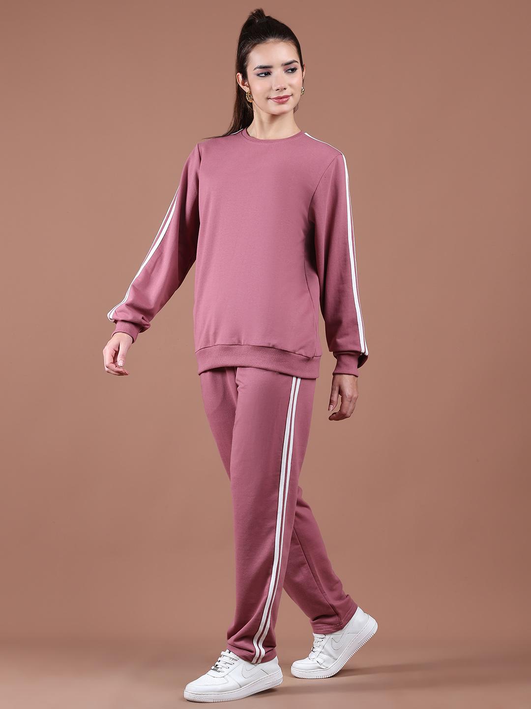 Woman wearing a mauve tracksuit with white stripes on a brown background